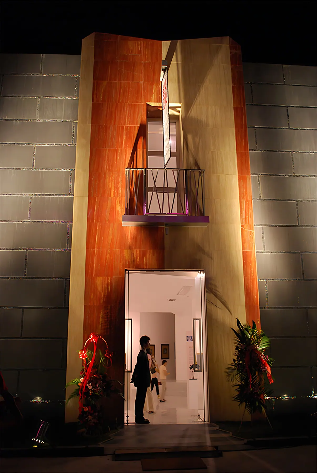Gallery entrance at night with a tall orange-clad portal and small balcony, Shengling Gallery, Shanghai
